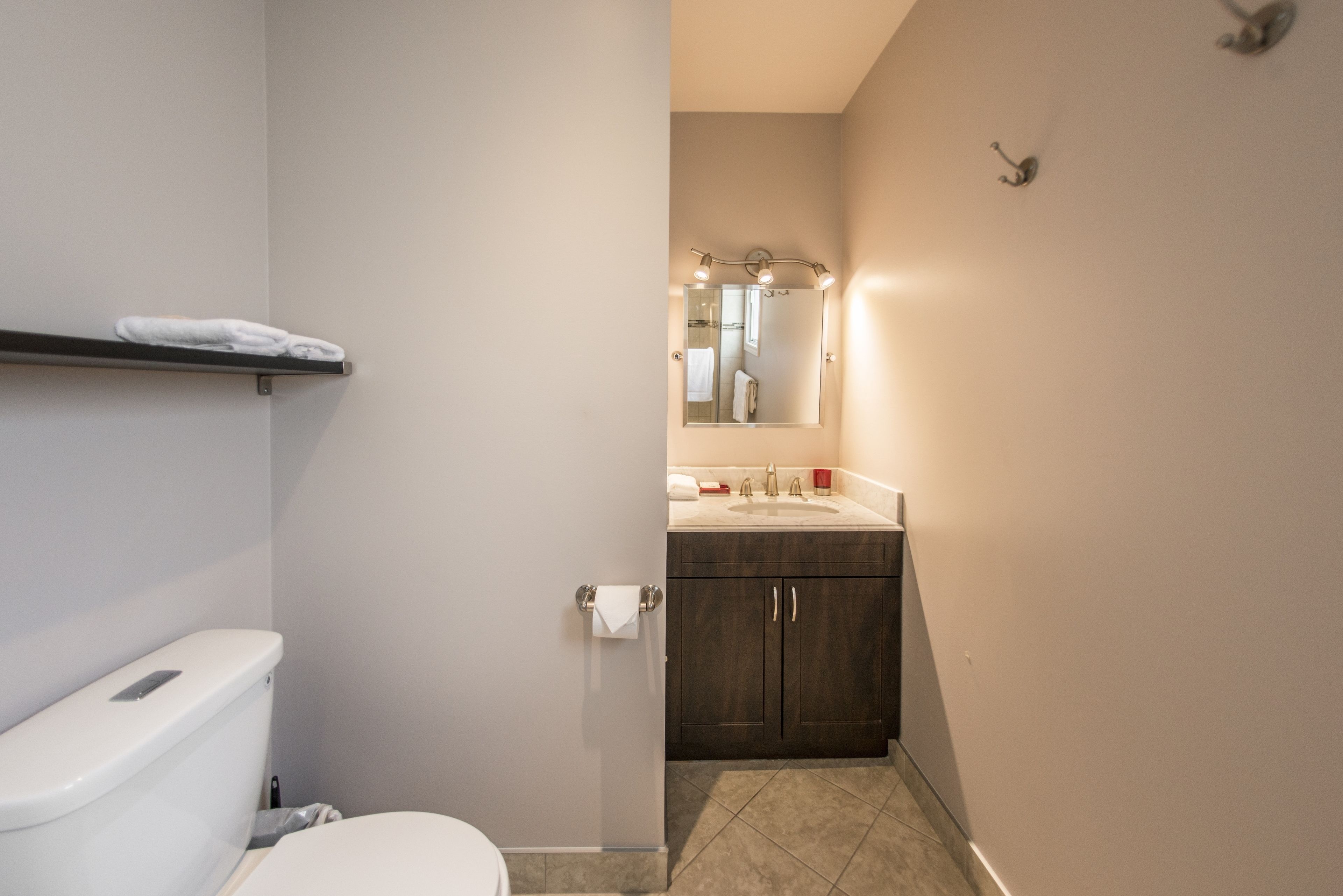 Ein Badezimmer mit Toilette, Waschbecken, Spiegel und Handtuchhalter.