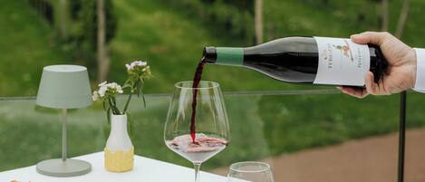 A table set with a wine bottle being poured into a glass, a plate of food, a water glass, and a lamp.