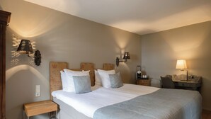 A hotel room with a large bed, a desk, a chair, and a nightstand. - Hotel Winselerhof by Flow (Landgraaf)