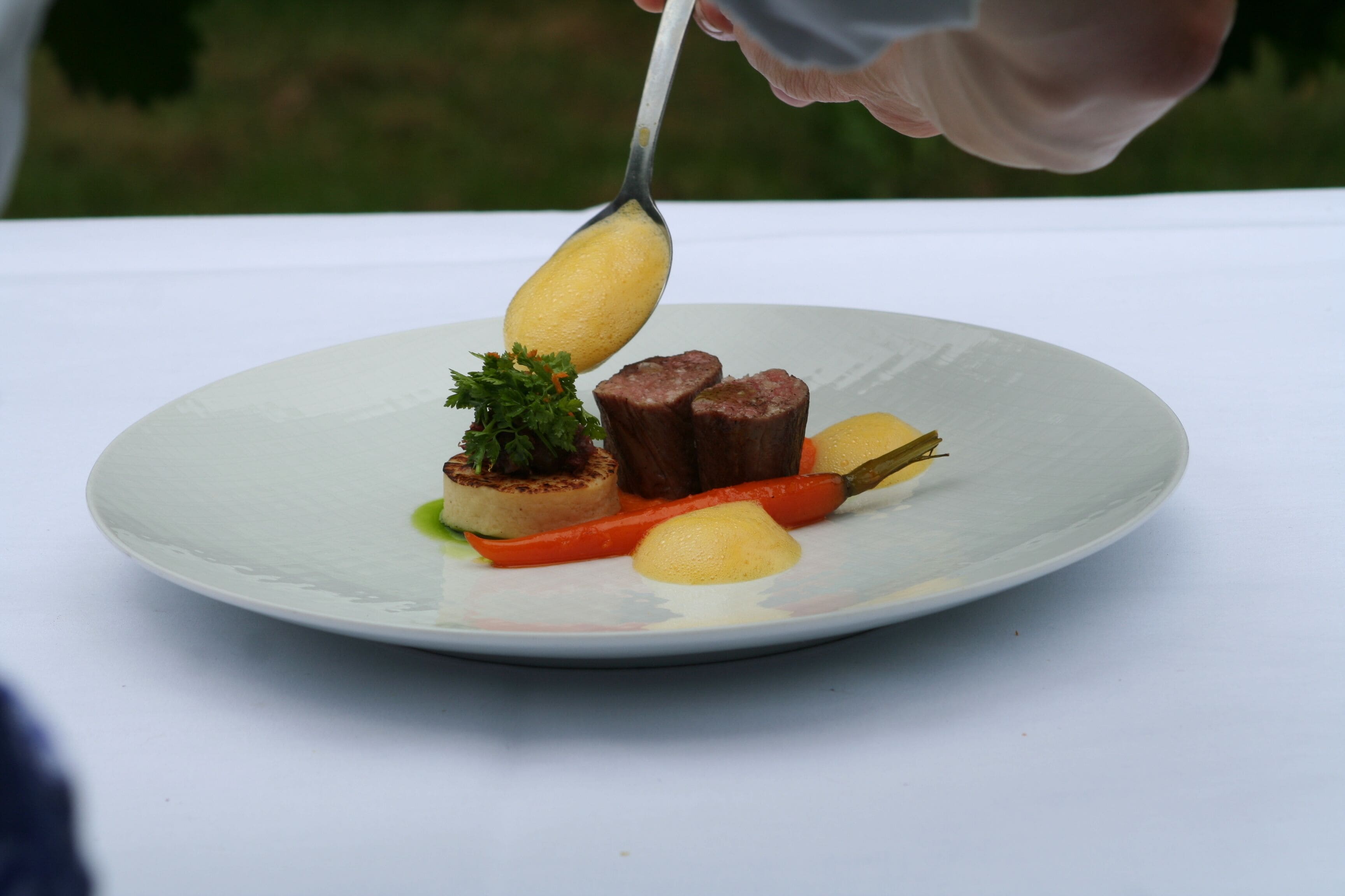 A plate with a piece of meat, a vegetable, and a garnish.