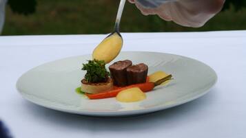 Une assiette comprenant un morceau de viande, un légume et une garniture.