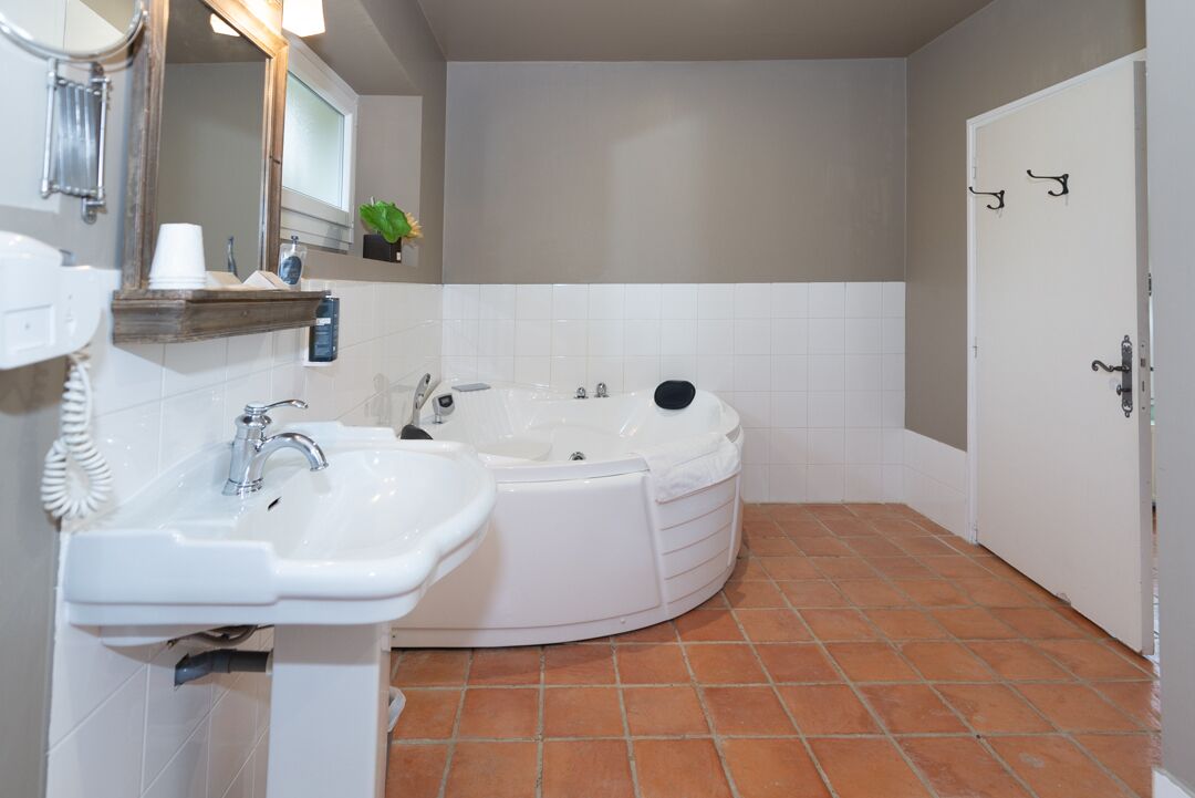 A bathroom with a sink, mirror, and bathtub.