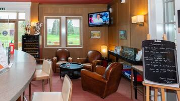 Un rincón lounge acogedor con sillones de cuero, bar y pantalla de televisión.