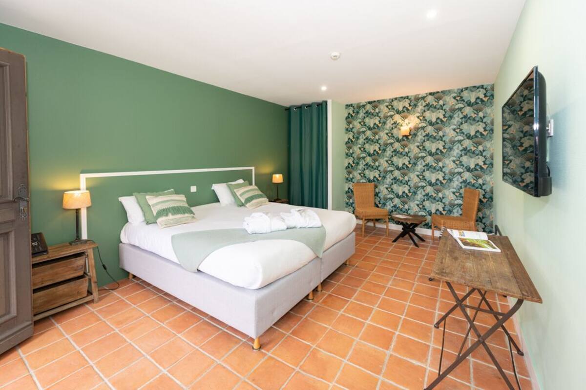 Een hotelkamer met een bed, twee stoelen, een tafel en een televisie.