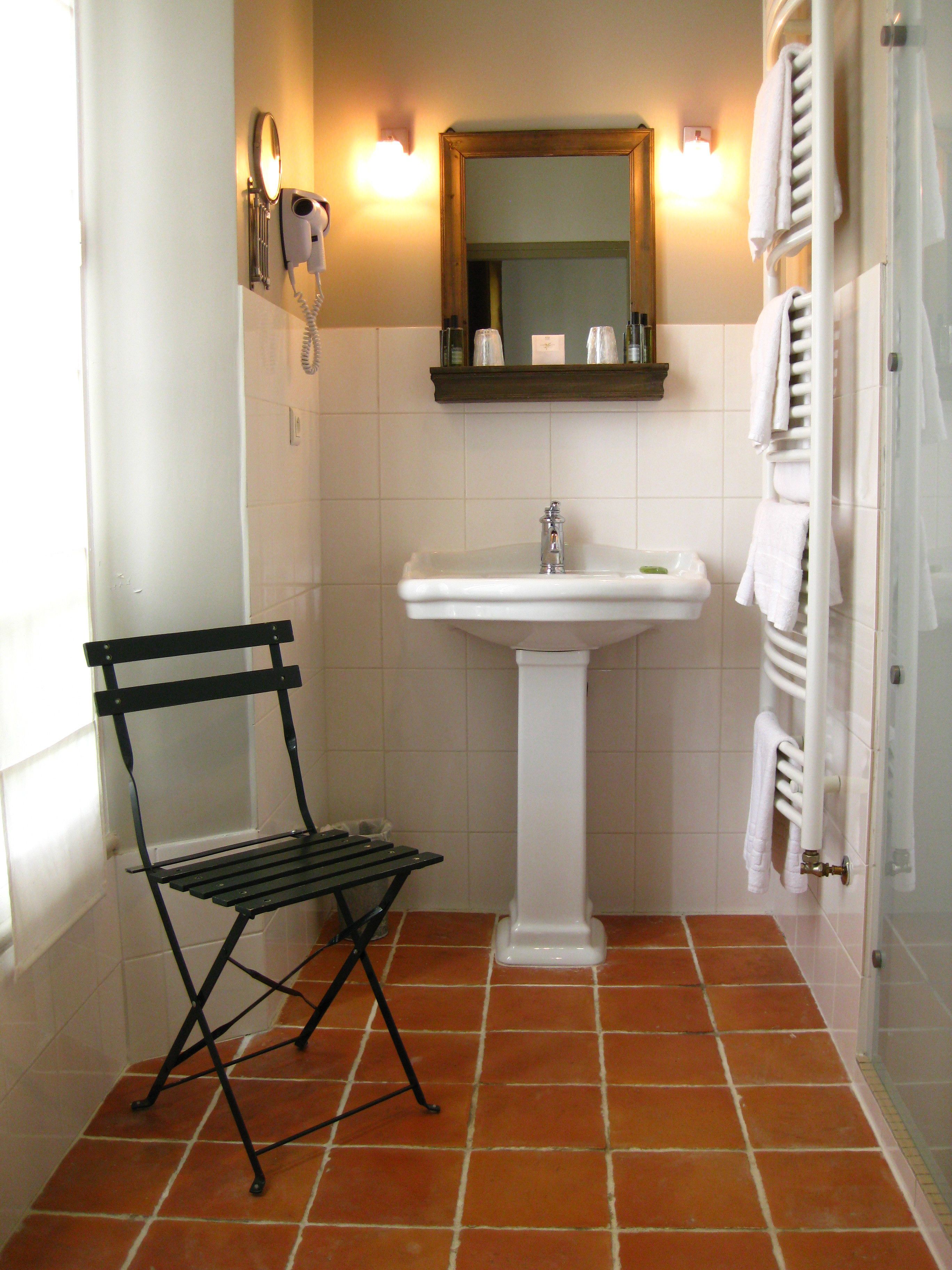 Een badkamer met een witte wasbak, een spiegel erboven en een handdoekrek aan de rechterkant.