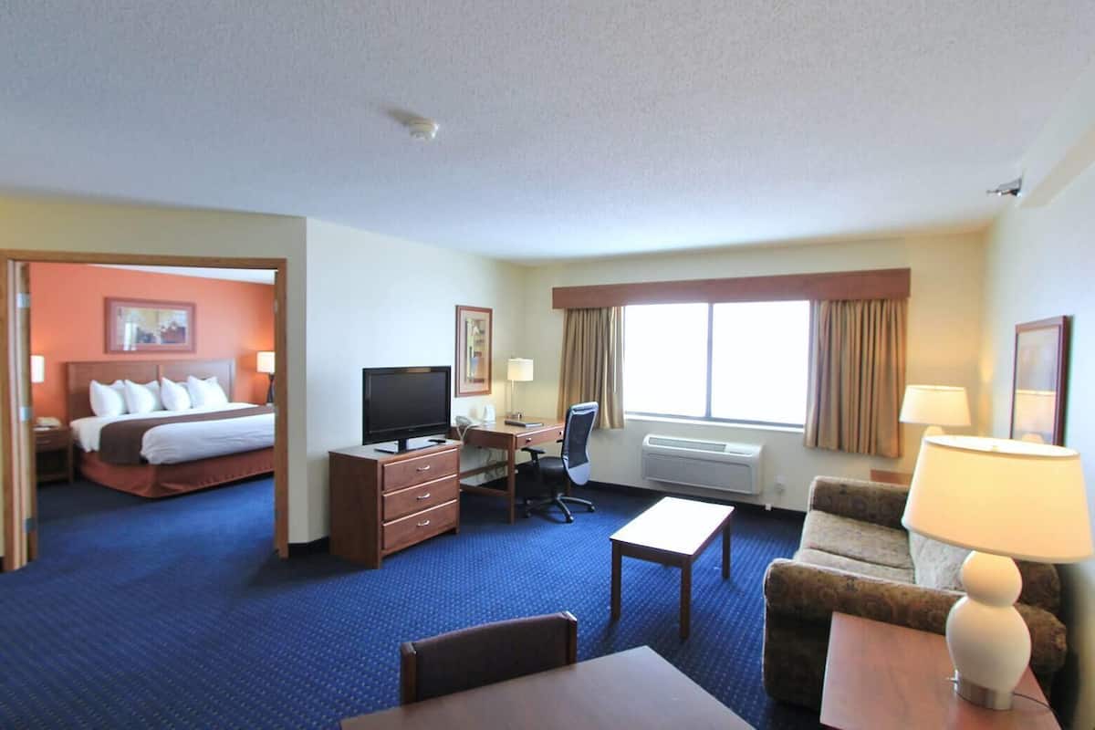 Ein Hotelzimmer mit Bett, Schreibtisch, Fernseher, Sessel, Sofa und Lampe.