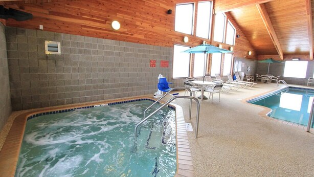 Una piscina interior con techo de madera, paredes de azulejos y señal de profundidad de spa.