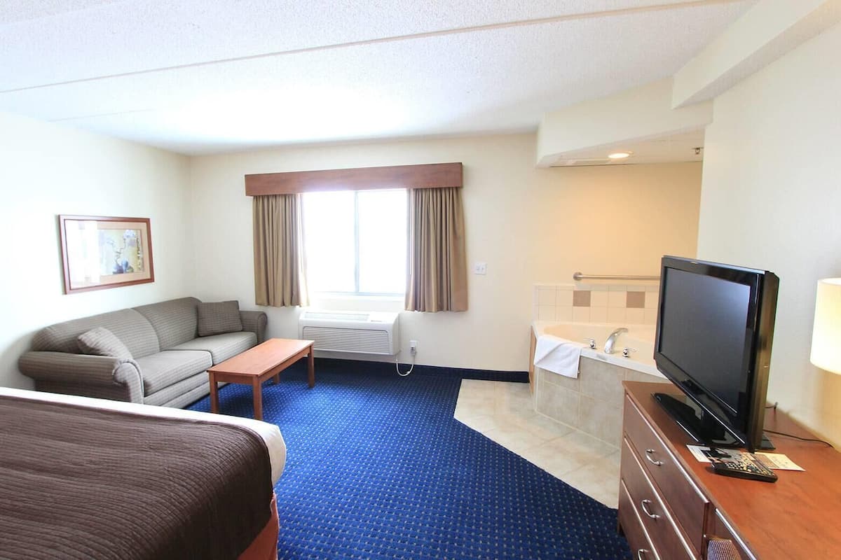 Ein Hotelzimmer mit Bett, Sofa, Schreibtisch, Fernseher und Bad.