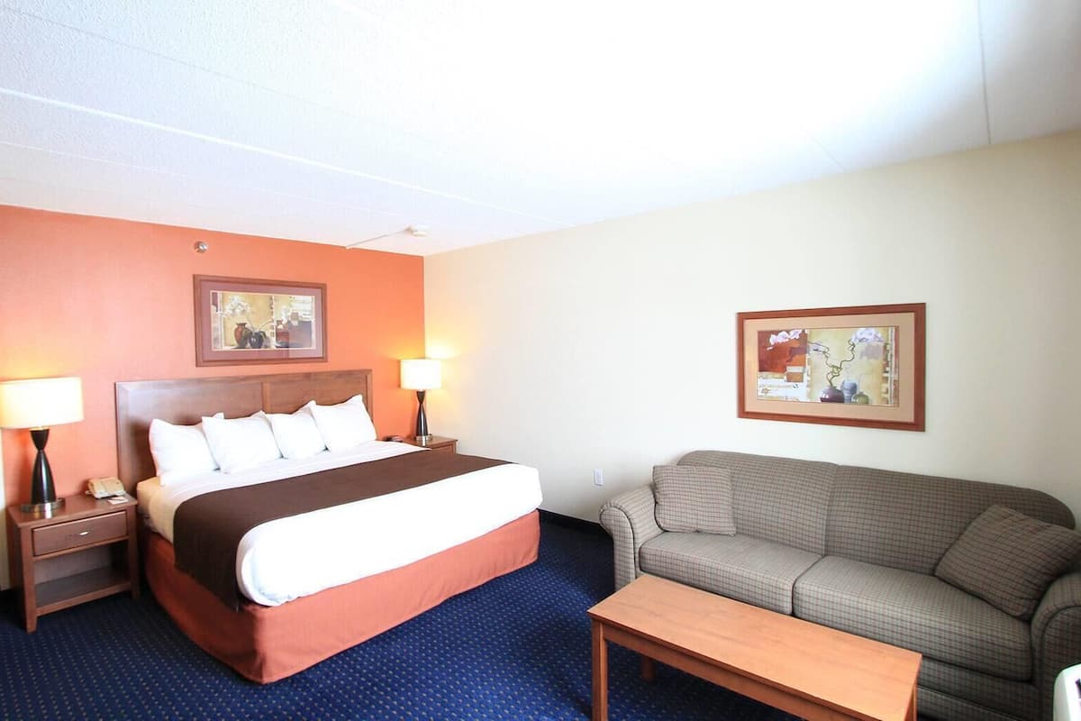 Ein Hotelzimmer mit einem Bett, einer Couch, einem Couchtisch und zwei Lampen.