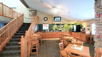 A restaurant with wooden furniture, a kitchen area, and a staircase.