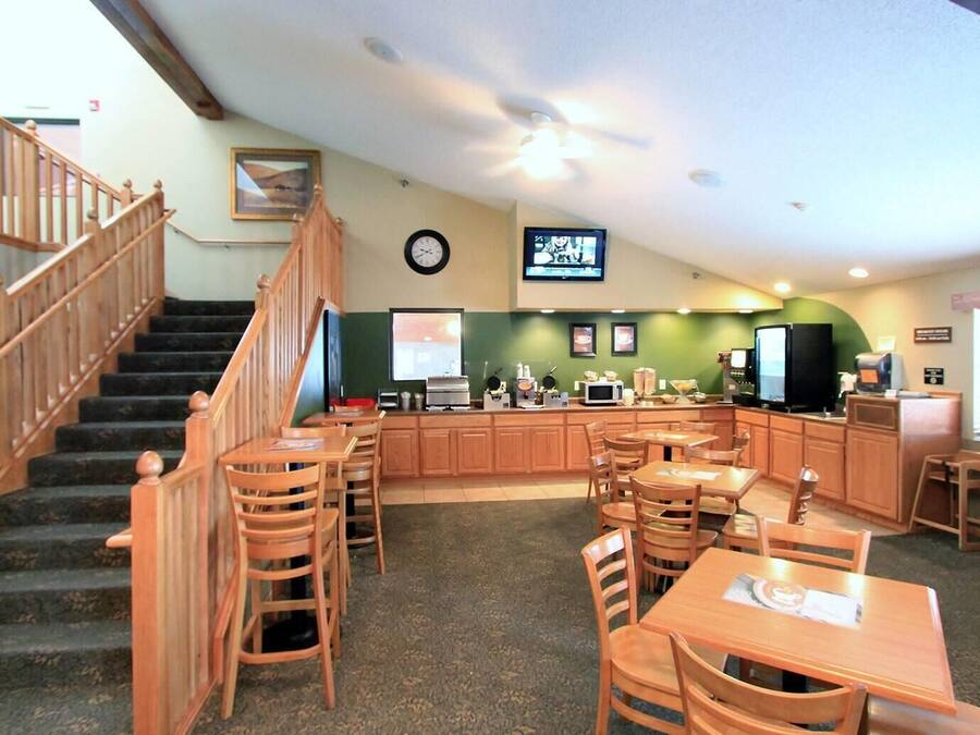 A restaurant with wooden furniture, a kitchen area, and a staircase.