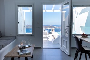 Una habitación moderna con vista al mar, un comedor con mesa y sillas, y un sofá.