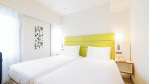 A hotel room with two beds, a green headboard, white bedding, a nightstand with a lamp, and a wall-mounted phone. - Holiday Inn Ana Sapporo Susukino by IHG (Sapporo)
