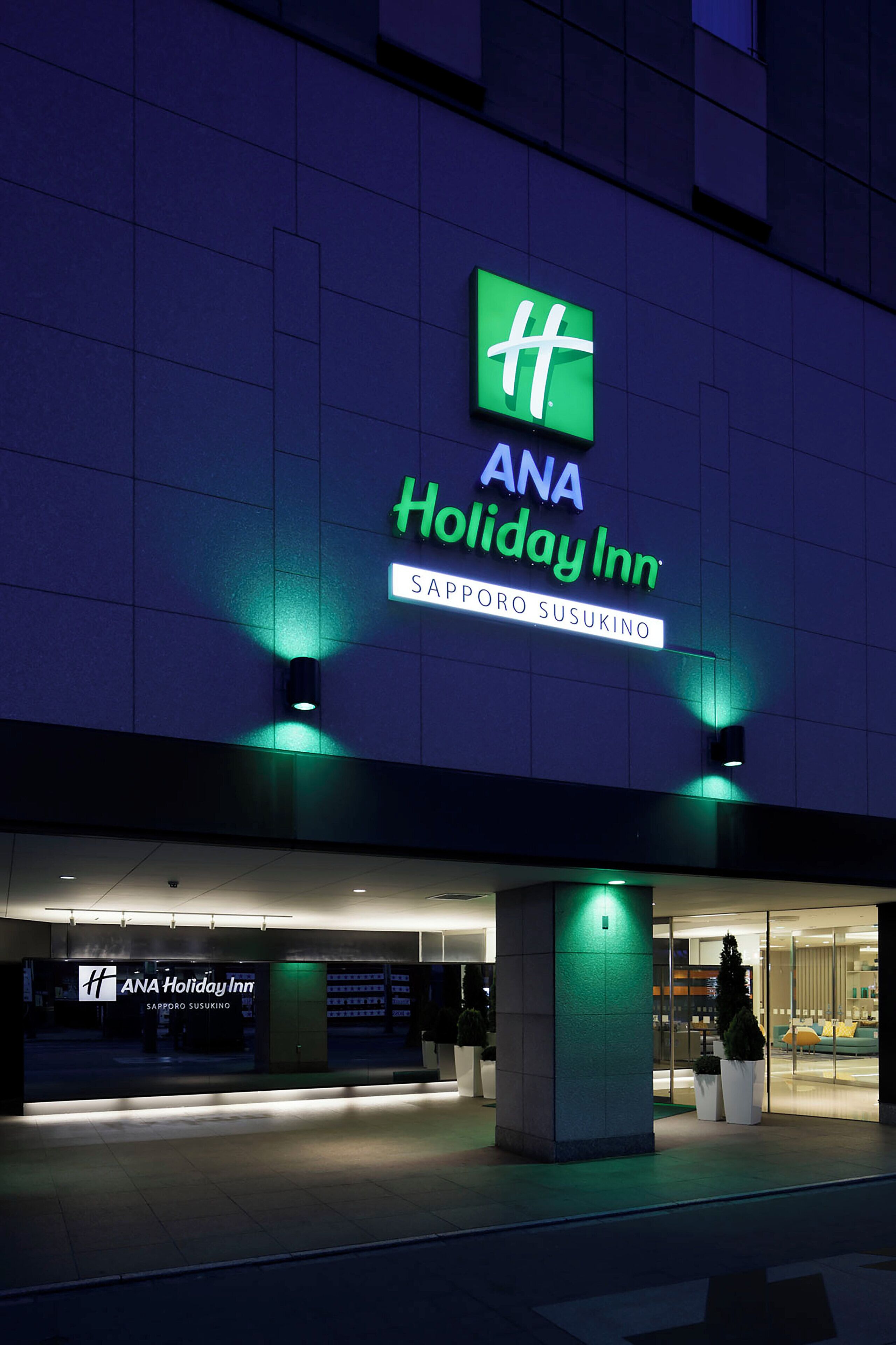 The exterior of ANA Holiday Inn with a prominent sign and a well-lit entrance.