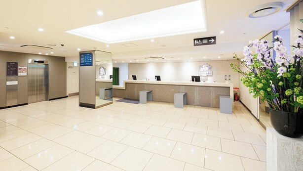 A clean, modern reception area with a reception desk, a digital directory, and a staircase leading to an elevator. - Holiday Inn Ana Sapporo Susukino by IHG (Sapporo)