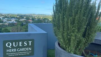 Señal del Jardín de Hierbas Quest con vista a una zona residencial al fondo.