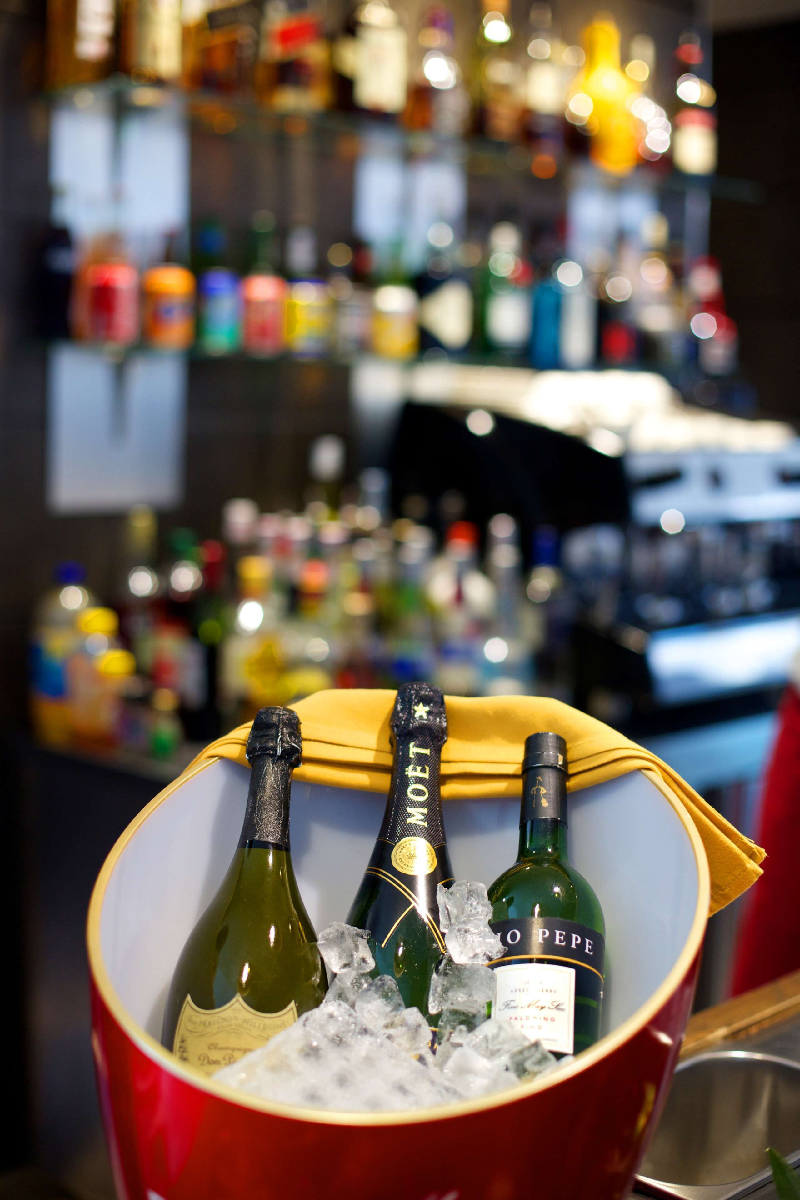 A bucket containing three bottles of wine, ice, and a yellow napkin.