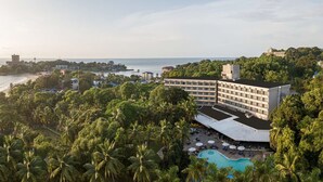 Un hotel con piscina, rodeado de exuberante vegetación y vistas al mar.
