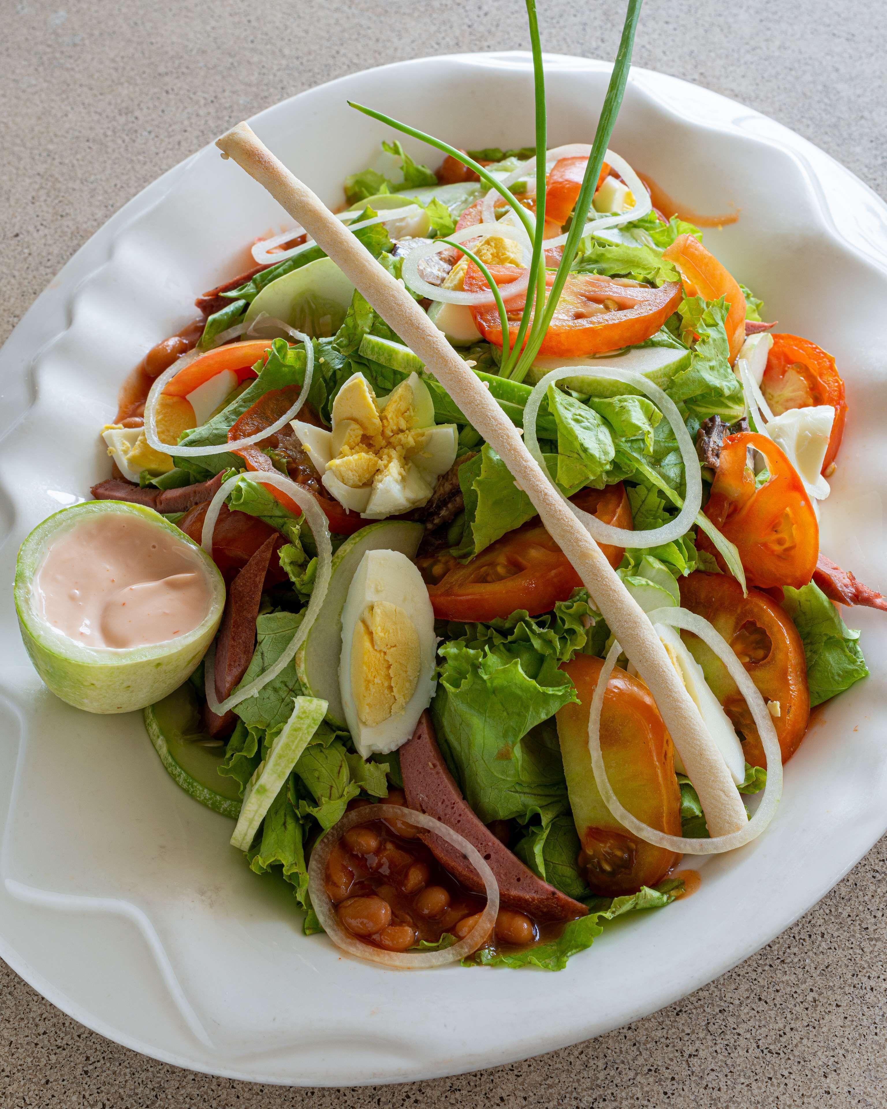 A salad with various ingredients including lettuce, tomatoes, and eggs.