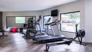 A gym with treadmills, elliptical machines, and exercise balls.