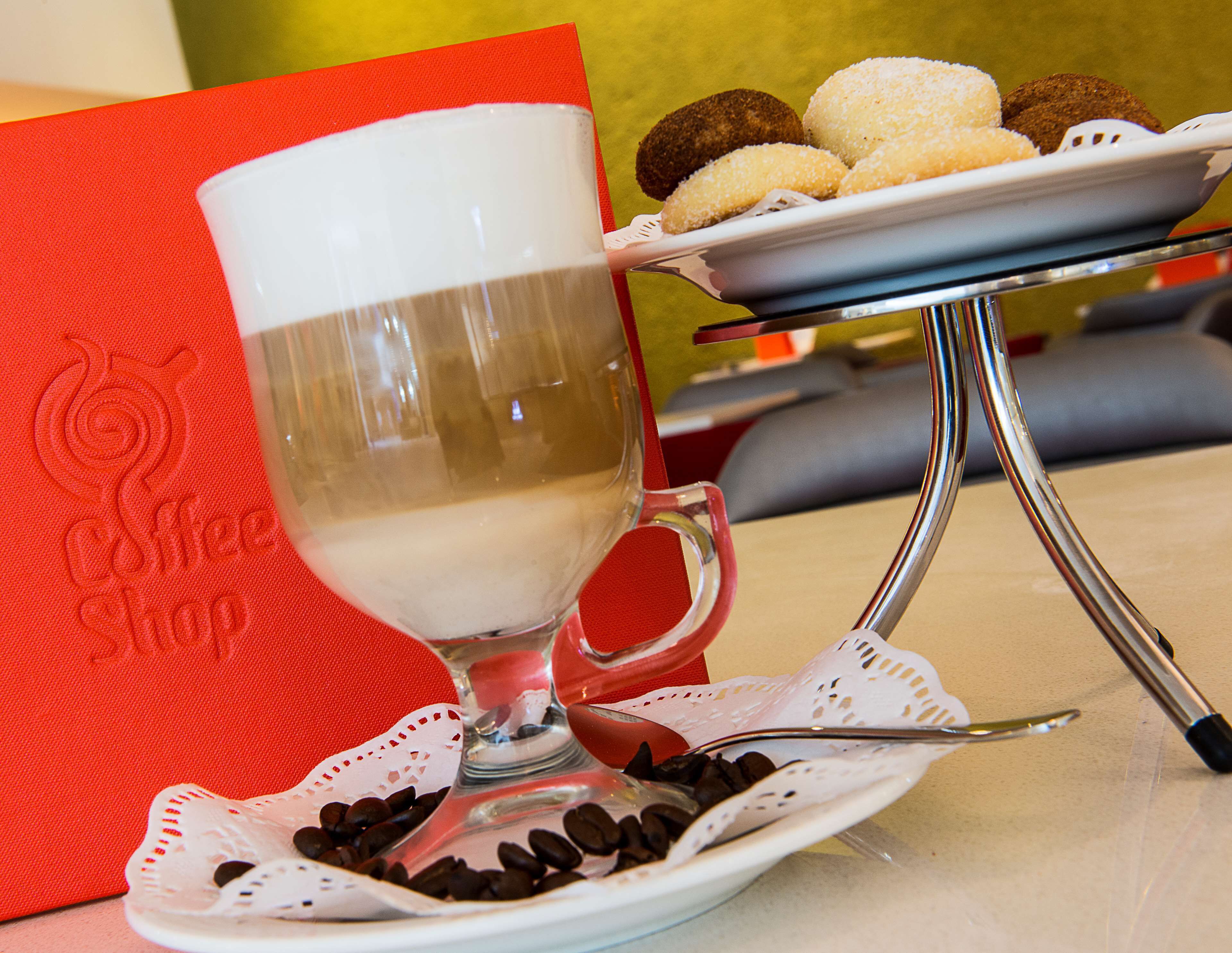 A coffee shop setting with a glass of milk, a plate of cookies, and a coffee cup on a table.