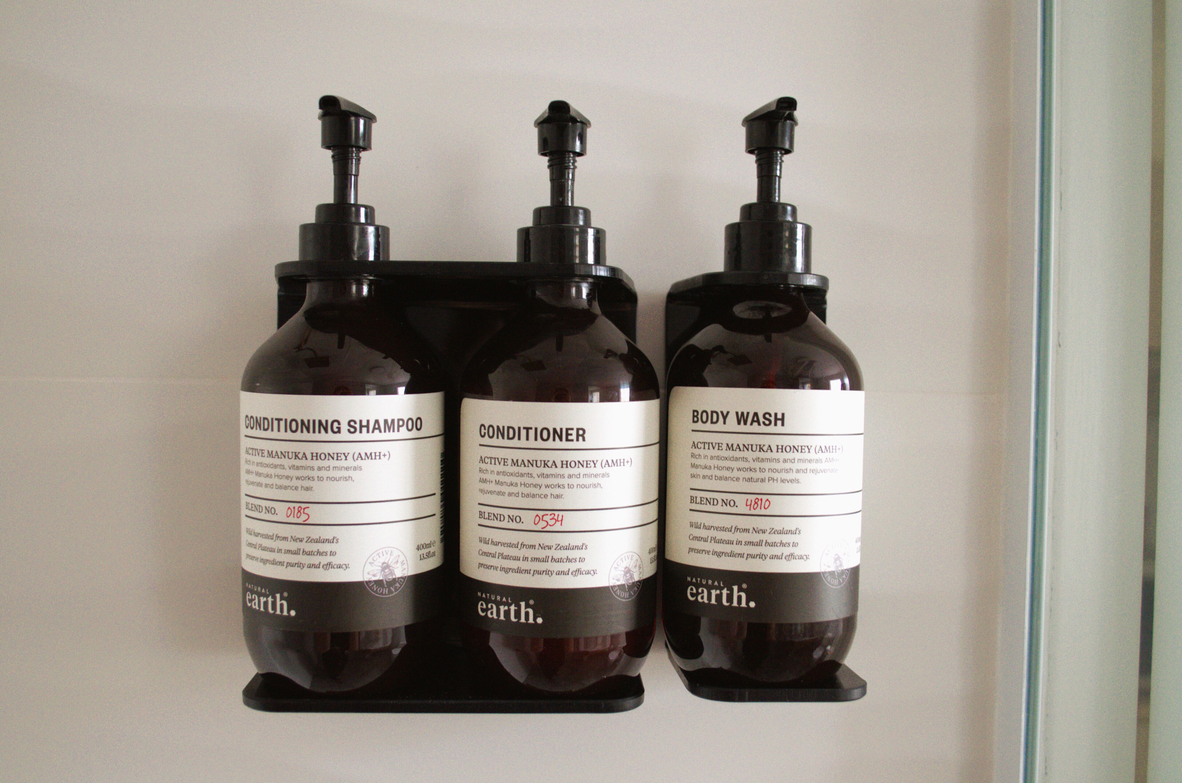 Three bottles of natural hair care products on a shelf.