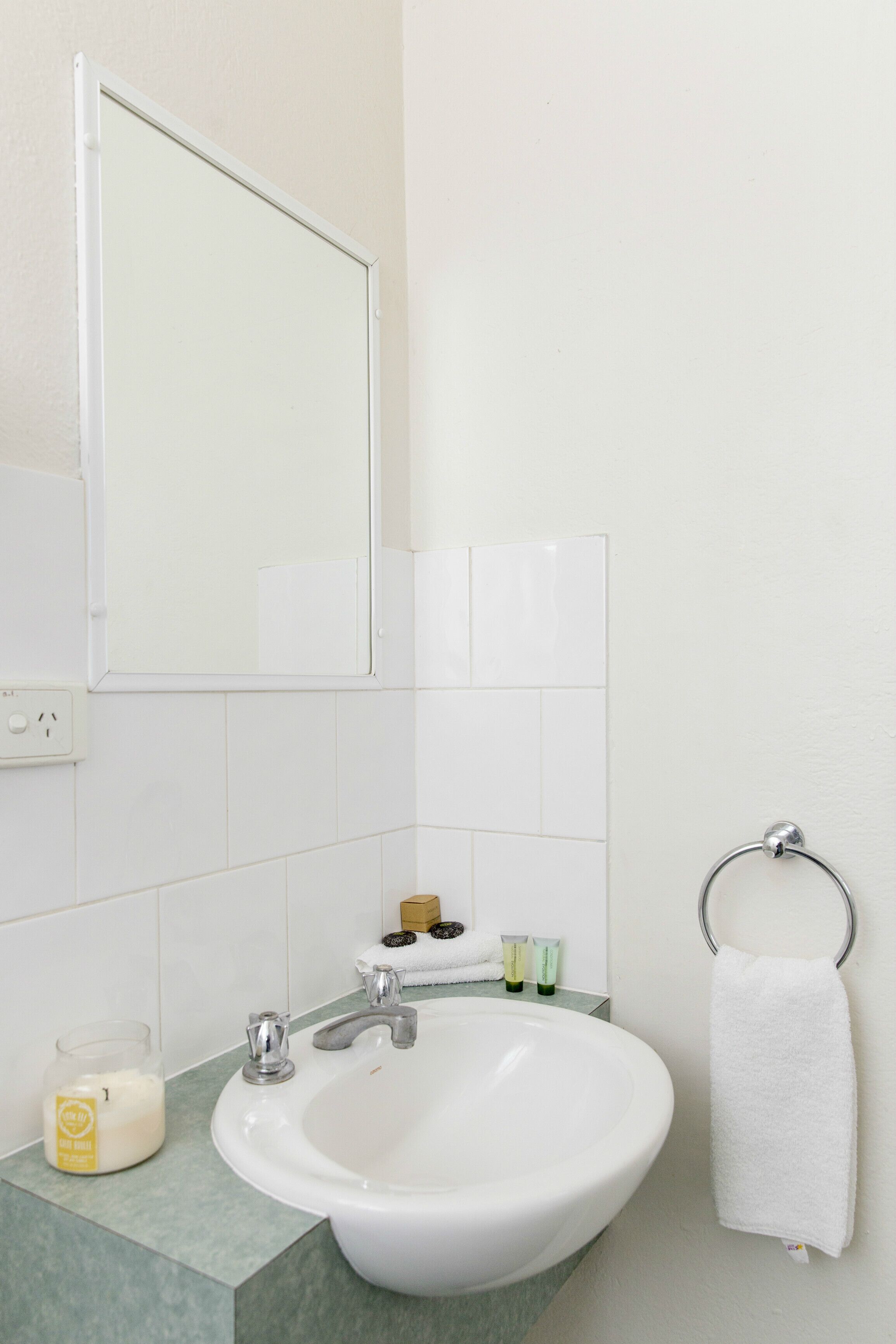 A bathroom with a white sink, mirror, and towel ring.
