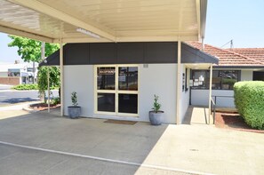 A reception area with a sign, a covered entrance, and potted plants. - Bathurst Motor Inn (Bathurst)