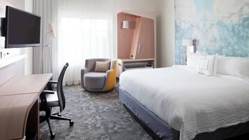 Una habitación de hotel con cama, escritorio, silla, armario y televisor.