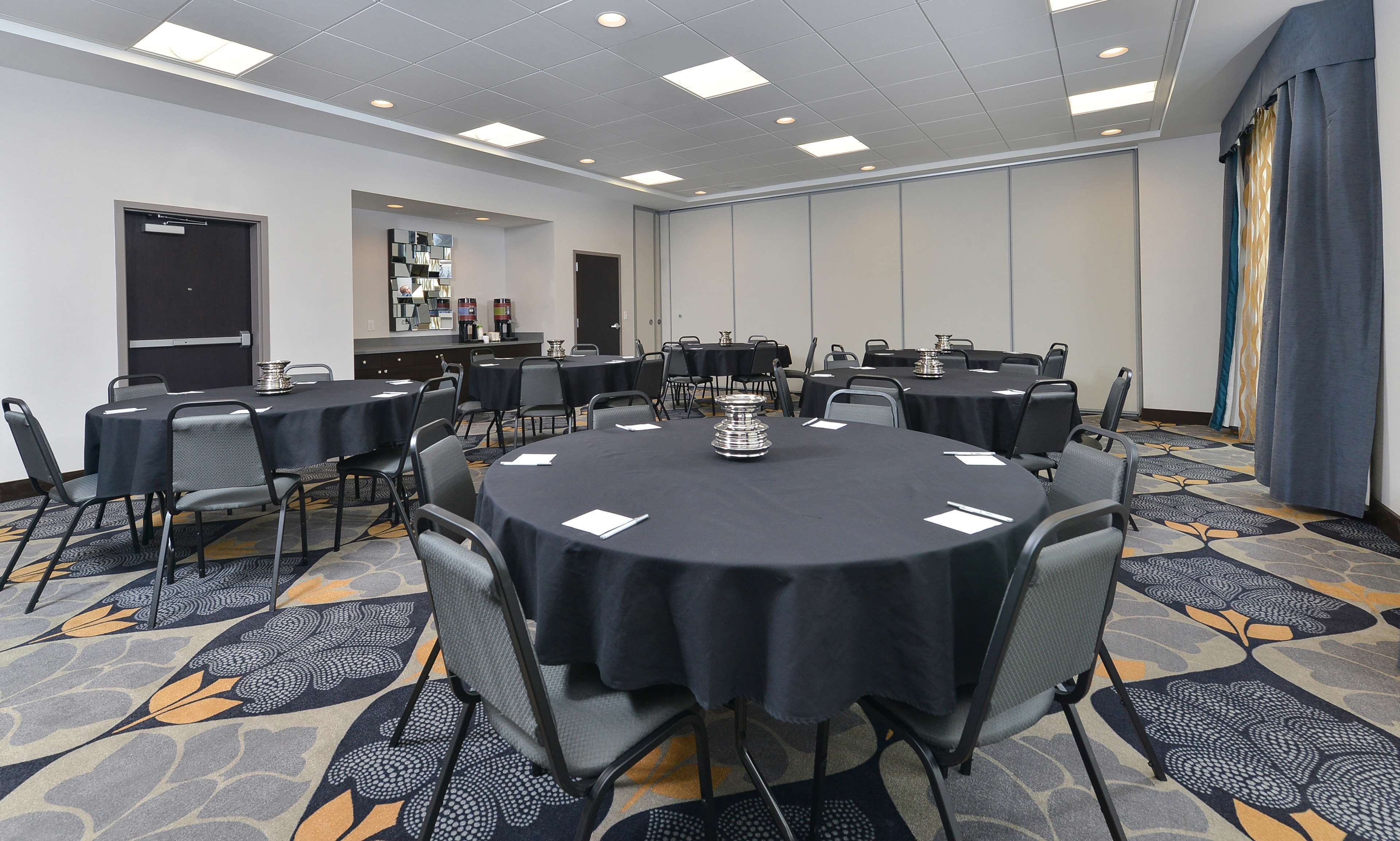 A conference room with round tables, chairs, and a coffee station.