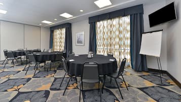A conference room with round tables, chairs, a whiteboard, and patterned carpet.
