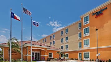 Un hotel con un cartel que dice "TownePlace Suites by Marriott" y varias banderas, incluyendo la bandera del estado de Texas.