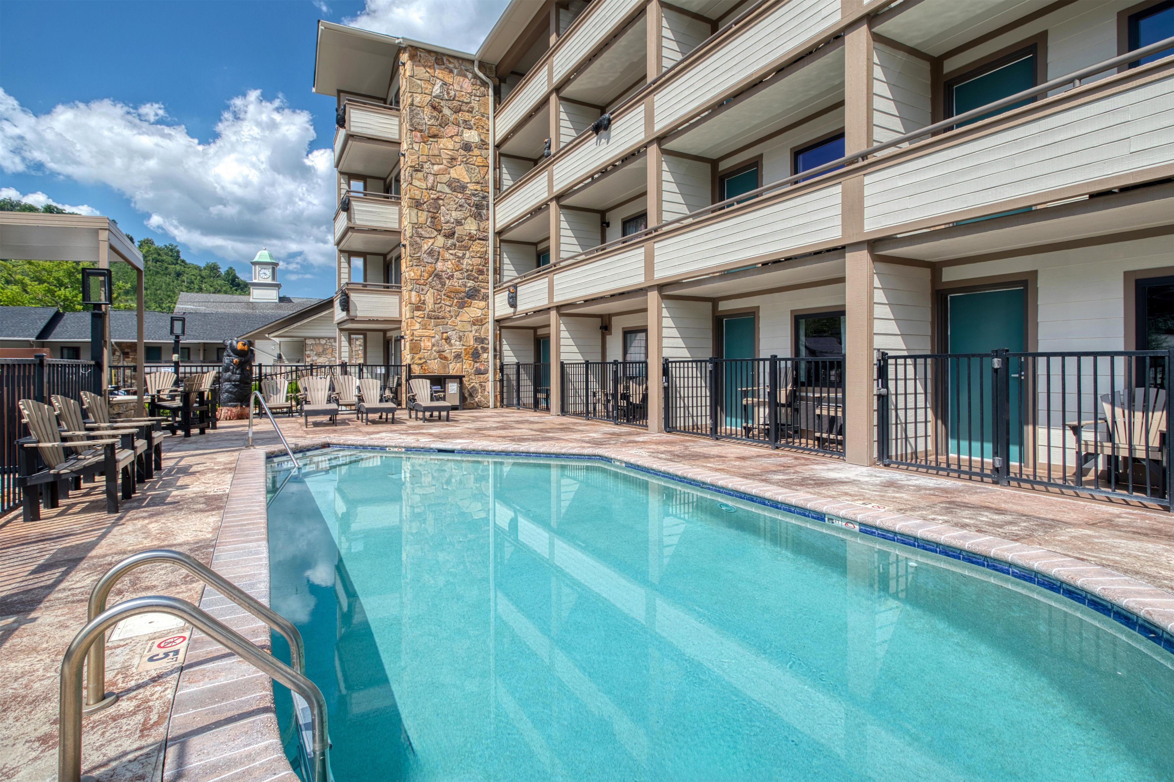 A hotel with a swimming pool, outdoor seating, and a stone tower.