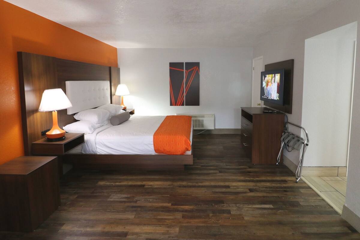 Une chambre d’hôtel avec un lit, deux lampes de chevet, une télévision, un petit bureau et une chaise.