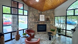 A cozy room with a stone fireplace, large windows, and a wooden ceiling. - Best Western Johnson's Inn Downtown Gatlinburg (Gatlinburg)