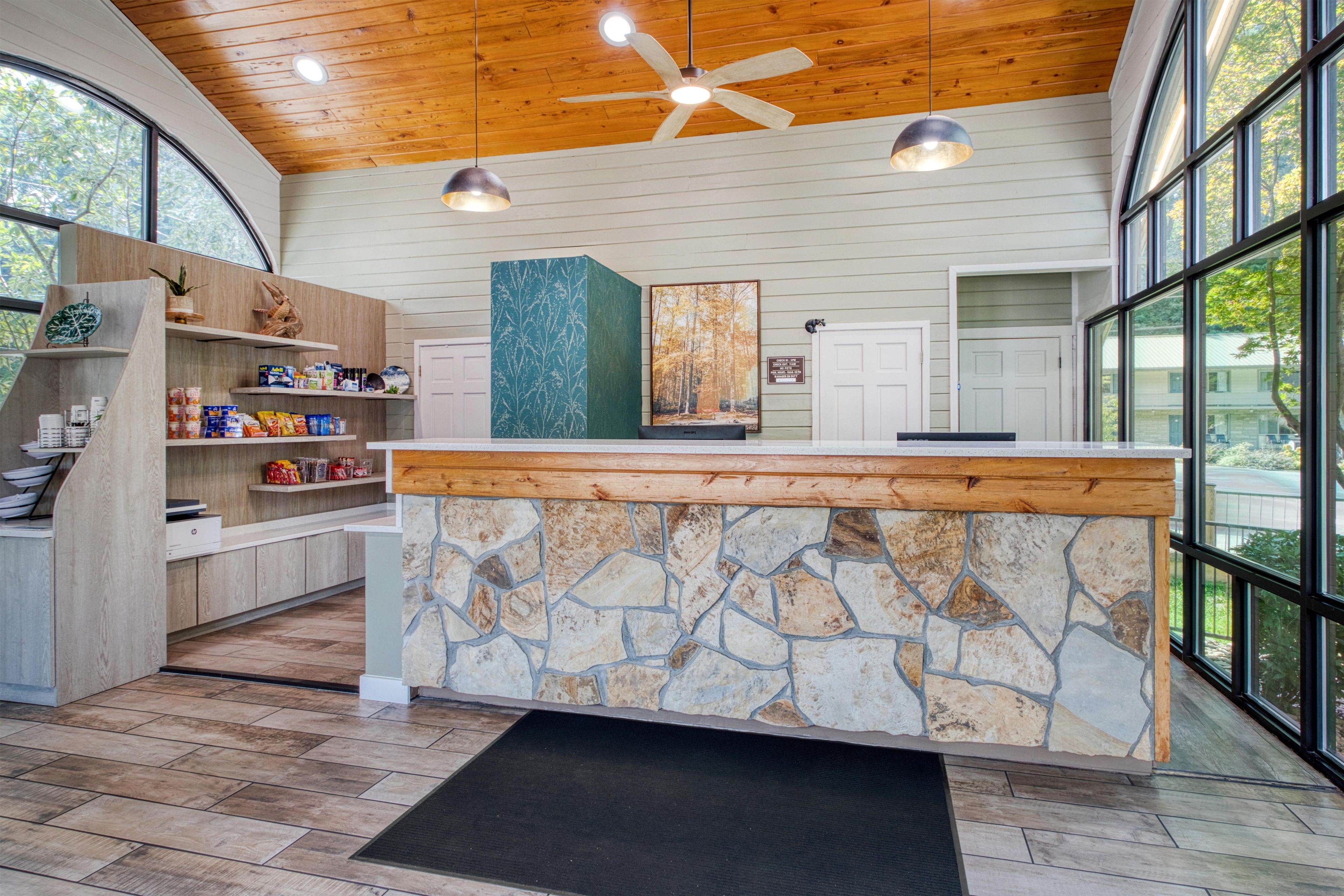 Una cocina moderna con una isla de piedra, armarios de madera y ventanas amplias.