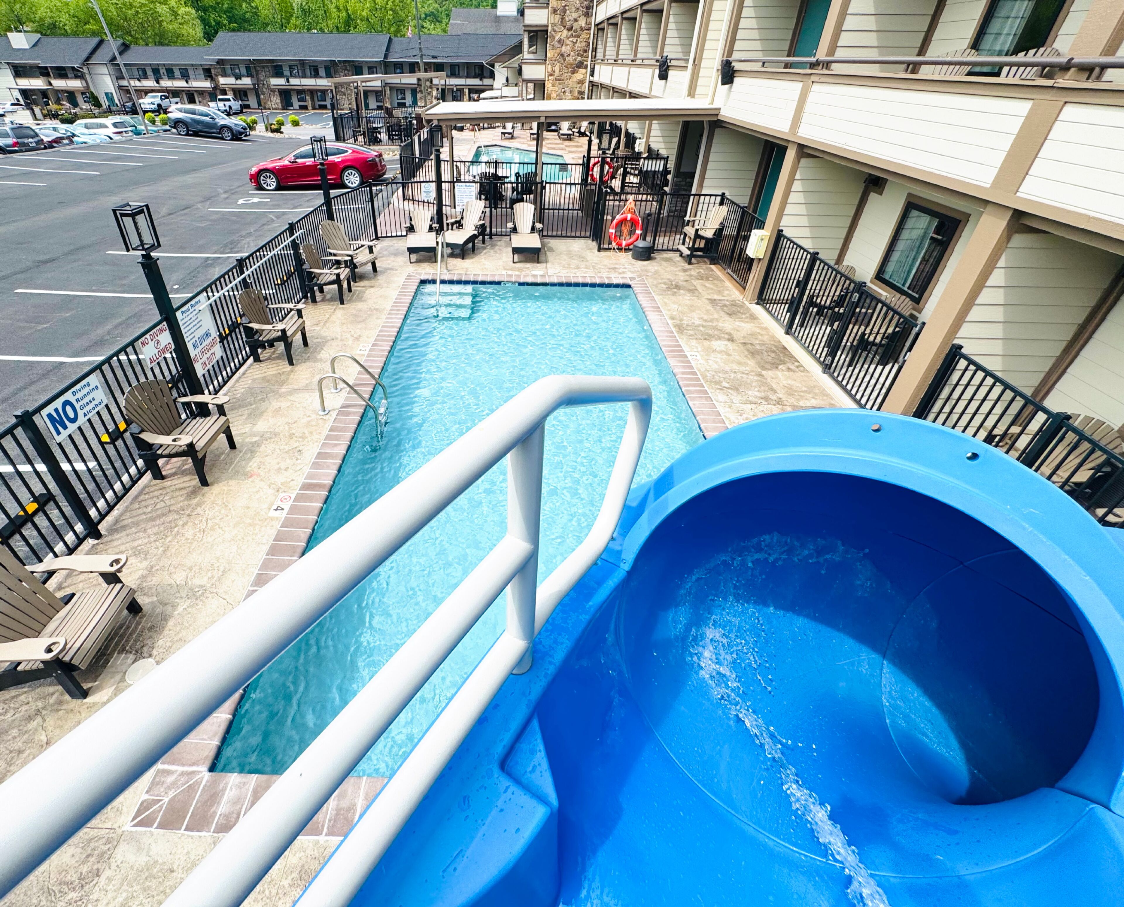 A pool area with a blue slide, lounge chairs, and a view of the hotel buildings.