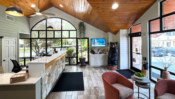 A spacious room with a wooden ceiling, a large window, a reception desk, and a bear statue. - Best Western Johnson's Inn Downtown Gatlinburg (Gatlinburg)