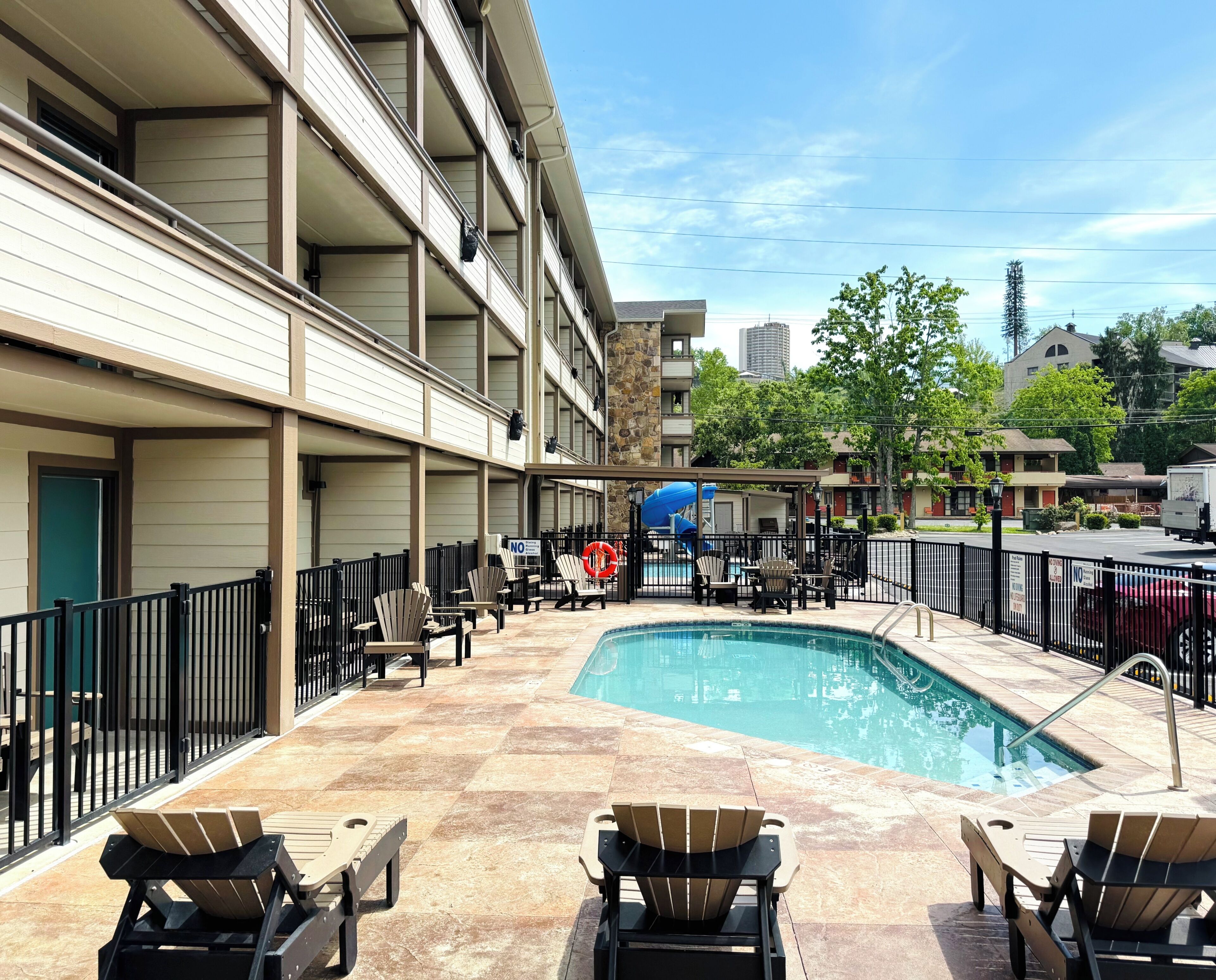 Un espace piscine d’hôtel comprenant plusieurs chaises longues, une piscine et un bâtiment doté de balcons.