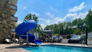 A swimming pool with a blue slide, lounge chairs, and a stone building. - Best Western Johnson's Inn Downtown Gatlinburg (Gatlinburg)