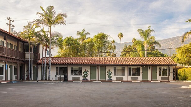 Un motel con techo de tejas, varias habitaciones y un estacionamiento.