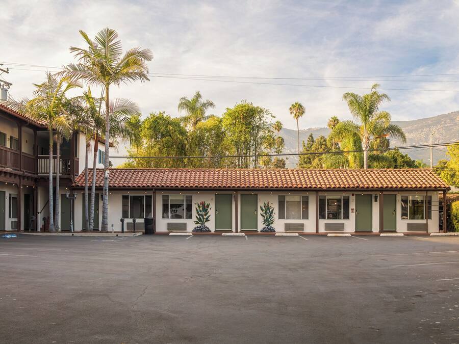Un motel con techo de tejas, varias habitaciones y un estacionamiento.
