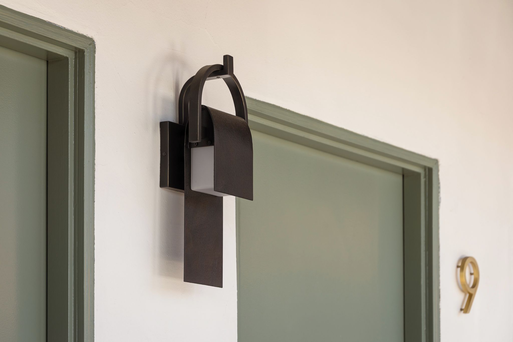 A wall-mounted light fixture with a rectangular base and a curved arm.