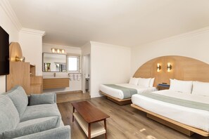 A hotel room with a sofa, a bed, a wooden headboard, a mirror, and a TV. - Solei House (Santa Barbara)