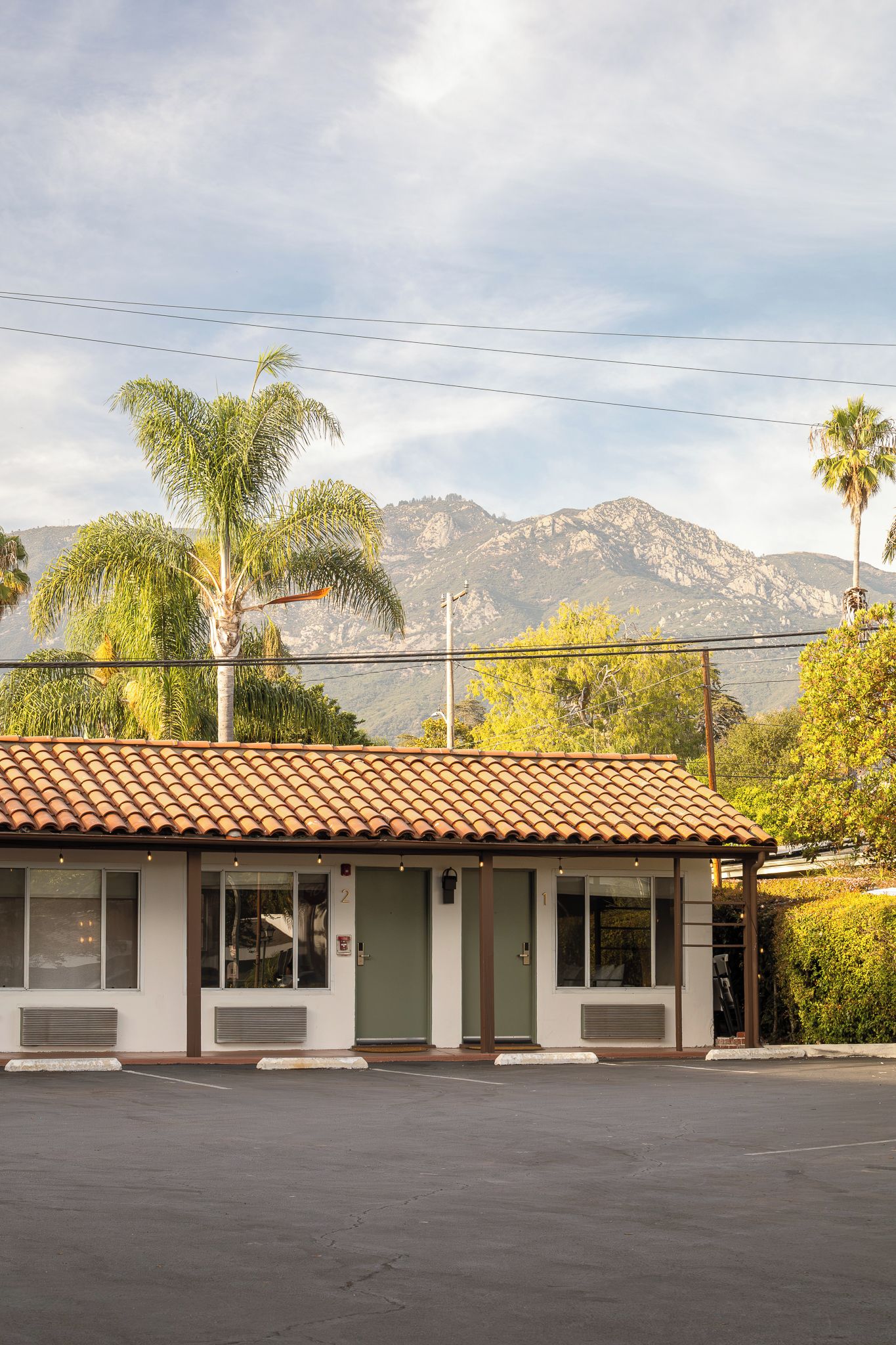 A building with a tiled roof, two doors, and a small parking lot.