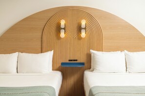 A hotel room with a wooden headboard, two beds, white bedding, and a blue bedside table. - Solei House (Santa Barbara)