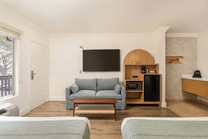 Sala de estar com sofá, mesa de centro, televisão de tela plana, micro-ondas e geladeira.