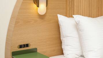 Un dormitorio con cabecera de madera, una mesita de noche con bandeja verde y una lámpara de pared.
