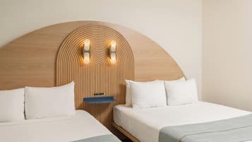 A hotel room with two beds, a wooden headboard, and a wall-mounted light fixture.