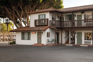 Un immeuble de deux étages doté d’un balcon, d’une enseigne indiquant qu’il s’agit de bureaux, et d’un parking situé devant.